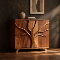 Two door sideboard with a carved tree branch relief across the doors, three-quarter view showing the grain