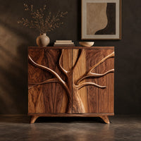 Corner detail of two door sideboard with a carved tree branch relief across the doors beside wood, brass and linen samples
