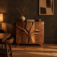 Two door sideboard with a carved tree branch relief across the doors in a dark dining room at golden hour