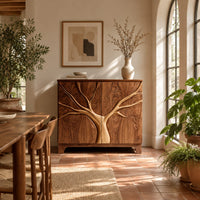 Two door sideboard with a tree carved in relief across both doors in a bright dining room with arched windows and plants