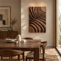 Carved wooden wall panel with sweeping layered grooves beside a dining table in natural light