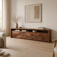 Long tv stand with four carved doors showing ocean waves and a rising sun in a Scandinavian living room with white walls