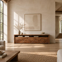 Long tv stand with four carved doors showing ocean waves and a rising sun in a bright open plan living room