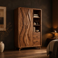 Wardrobe with carved wave pattern doors beside open shelves and three drawers in a dark bedroom at golden hour