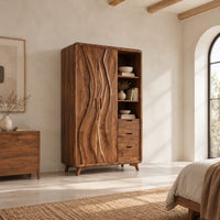 Wardrobe with carved wave pattern doors beside open shelves and three drawers in a bright open plan bedroom