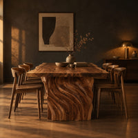 Dining table with a natural edge slab top and two carved wave pedestals in a dark dining room at golden hour