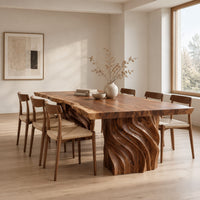 Dining table with a natural edge slab top and two carved wave pedestals in a Scandinavian dining room with white walls