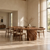 Dining table with a natural edge slab top and two carved wave pedestals in a bright open plan dining room