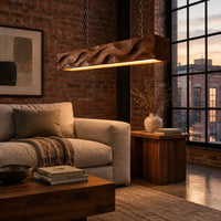 Long wood pendant light with carved waves and a warm glow along its underside in an industrial loft living room with exposed brick