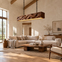 Long wood pendant light with carved waves and a warm glow along its underside in a bright open plan living room