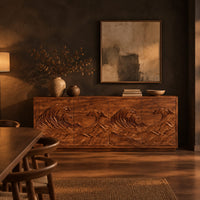 Sideboard with four doors carved in a rolling ocean wave relief in a dark dining room at golden hour