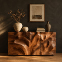 Sideboard with three flush doors and a rolling carved wave relief front in a dark studio against a charcoal plaster wall