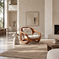 Chair with a sculpted open loop wood frame and tufted cream cushions in a bright open plan living room