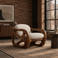 Chair with a chunky sculpted frame, large oval cutouts and a pillow back in an industrial loft living room with exposed brick