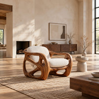 Chair with a chunky sculpted frame, large oval cutouts and a pillow back in a bright open plan living room