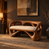 Bench with a looped wooden frame, cutout back and cream cushion in a dark entryway at golden hour