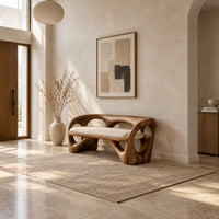 Bench with a looped wooden frame, cutout back and cream cushion in a bright open plan entryway