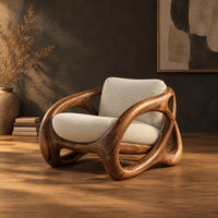 Chunky looped wood frame chair with oval openings and a cream seat in a dark studio against a charcoal plaster wall