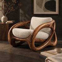 Corner detail of chunky looped wood frame chair with oval openings and a cream seat beside wood, brass and linen samples