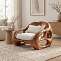 Chunky lounge chair with circular cutouts in thick sculpted arms in a Scandinavian living room with white walls