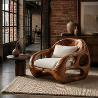 Chunky lounge chair with circular cutouts in thick sculpted arms in an industrial loft living room with exposed brick