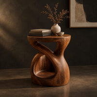 Chunky side table with a looping open body and thick flat top, three-quarter view showing the grain