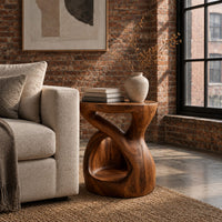 Chunky side table with a looping open body and thick flat top in an industrial loft living room with exposed brick