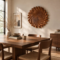 Circular wall art with spiral petal carving and a ruffled edge beside a dining table in natural light