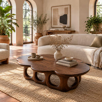 Cloud shaped coffee table on a base of round arches in a bright living room with arched windows and plants