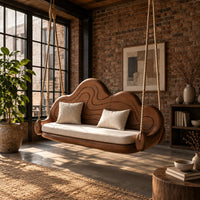 Cloud shaped swing with a carved wavy backrest and cream seat cushion in an industrial loft porch with exposed brick
