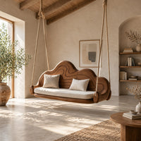Cloud shaped swing with a carved wavy backrest and cream seat cushion in a bright open plan porch