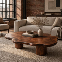 Low coffee table with a cloud shaped wavy top on thick cylinder legs in an industrial loft living room with exposed brick