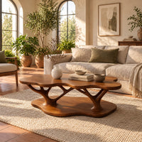 Coffee table with a cloud shaped top and branching legs in a bright living room with arched windows and plants