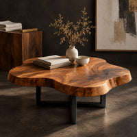 Corner detail of cloud shaped coffee table with a thick slab top on a slim cross base beside wood, brass and linen samples