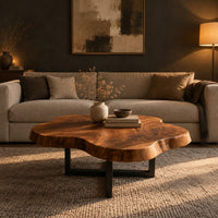 Cloud shaped coffee table with a thick slab top on a slim cross base in a dark living room at golden hour