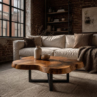 Cloud shaped coffee table with a thick slab top on a slim cross base in an industrial loft living room with exposed brick
