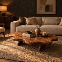 Cloud shaped coffee table with a thick wavy top and angled legs in a dark living room at golden hour