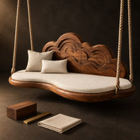 Corner detail of cloud shaped swing with a carved wave backrest and a cushioned seat beside wood, brass and linen samples