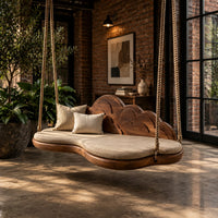 Cloud shaped swing with a scalloped carved back and a padded seat in an industrial loft porch with exposed brick