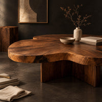 Corner detail of clover shaped coffee table with a thick top and cross shaped pedestal beside wood, brass and linen samples