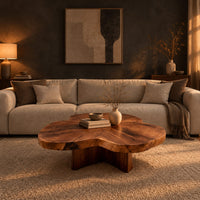 Clover shaped coffee table with a thick top and cross shaped pedestal in a dark living room at golden hour