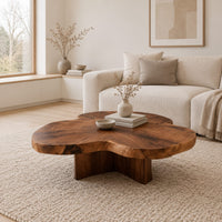 Clover shaped coffee table with a thick top and cross shaped pedestal in a Scandinavian living room with white walls