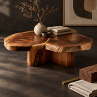 Corner detail of clover shaped coffee table with three joined slabs on a three fin base beside wood, brass and linen samples