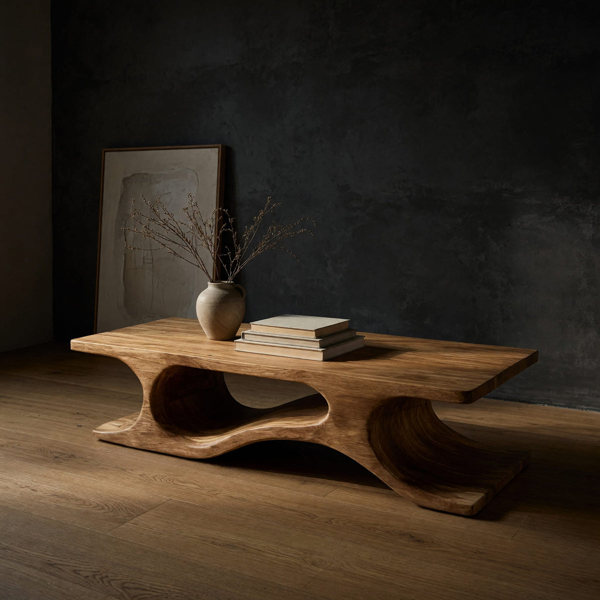 Minimal coffee table with an S curve waist base in a dark studio against a charcoal wall