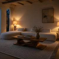 Minimal coffee table with an S curve waist base in an evening room lit by two lamps
