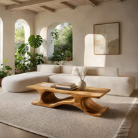 Minimal coffee table with an S curve waist base in a sunlit room with large windows and plants