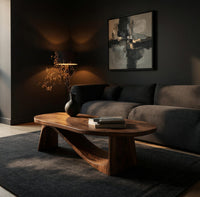 Coffee table on angled plank legs with a swooping brace in a living room at golden hour