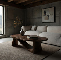 Coffee table on angled plank legs with a swooping brace in a concrete and timber loft