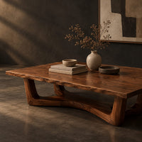 Corner detail of rectangular coffee table on an arched trestle base with a low curved beam beside wood, brass and linen samples
