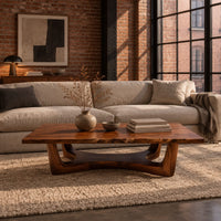 Rectangular coffee table on an arched trestle base with a low curved beam in an industrial loft living room with exposed brick